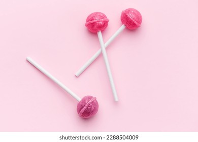 Colorful sweet lollipops over pink background.  Flat lay, top view