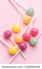 Colorful sweet lollipops over pink background.  Flat lay, top view