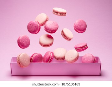 Colorful sweet macarons or macaroons, flavored cookies floating in the air above the paper box.