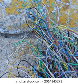 Colorful, Tangled Electrical Wires By A Yellow Roadside Curb. Sidewalk Scene.