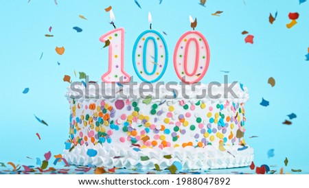 Colorful tasty birthday cake with candles shaped like the number 100.
