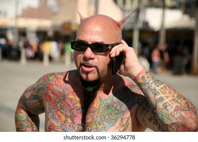 A Colorful Tattoo Artist Makes Deals On His Cell Phone While Outside
