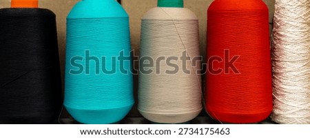 Colorful textile thread spools stacked warehouse show fiber production materials visible texture twist pattern detail. Circular rolls manufacturing process material quality order consistency