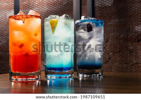 Colorful toned cocktails on wooden background. Frutal alcoholic cocktails. Colorful drinks concept on wooden table