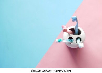  colorful toothbrushes in white mug against a wall  - Shutterstock ID 2069237501
