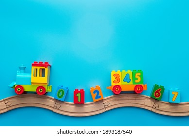 Colorful Toy Train Locomotive With Numbers On Wooden Railway On Blue Background. Kids Toys Background Banner. Early Childhood Education, Learning To Count, Preschool And Kids Game Concept.