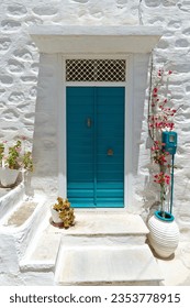Colorful traditional house entrance of the Cyclades islands, with a wooden green door and a white washed walls, as seen in Syros island, in Cyclades islands, Greece, Europe.