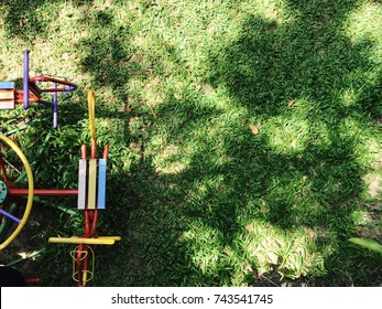 Colorful Traditional Metal Carousel/merry Go Round/roundabout On Playground In Sunny Day With Copy Space Of Shadow Of Trees On Lawn As Background - Childhood Holiday Joyful Memory Concept - Top View