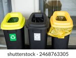 Colorful trash cans for sorting garbage. For plastic, glass, paper and others waste. Waste containers for garbage segregation in Poland, standing next to a wall