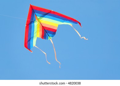 A colorful triangle, textile kite flying over blue sky