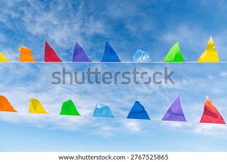 Colorful triangular flags fluttering in the wind against wispy clouds sky, symbolizing festivity and celebration