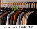 Colorful t-shirts lined up side by side on hangers. Clothes on wooden clothes rack.