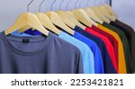 Colorful T-Shirts on wooden hanger hanging on clothing rack