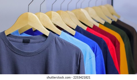 Colorful T-Shirts on wooden hanger hanging on clothing rack