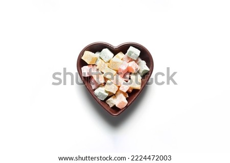 Colorful Turkish delights in a heart-shaped bowl. On a white background.