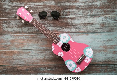 colorful ukulele with sunglasses on vintage wood background