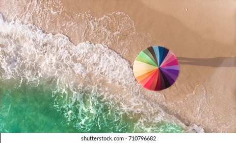 Colorful Of Umbrella On The Beach And Foam Of Sea Wave From Top Eye View Photo In Outdoor Sunlight Lighting.