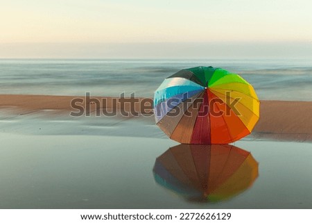 Similar – Colorful striped, closed parasol in close-up on the beach at sunset