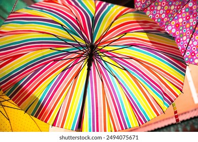 Colorful umbrella with vibrant rainbow stripes, creating a lively and cheerful pattern. Perfect for brightening up any rainy day or for use in outdoor markets and festive events. - Powered by Shutterstock