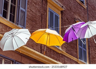 Colorful umbrellas create a vibrant canopy over a charming street in a scenic town of the Modena, Italy, - Powered by Shutterstock