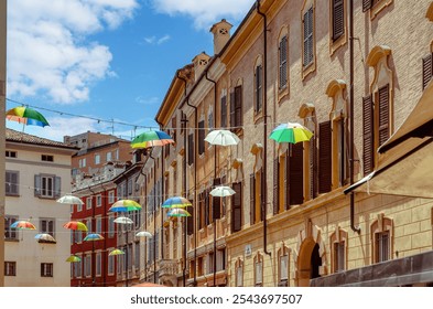 Colorful umbrellas create a vibrant canopy over a charming street in a scenic town of the Modena, Italy, - Powered by Shutterstock