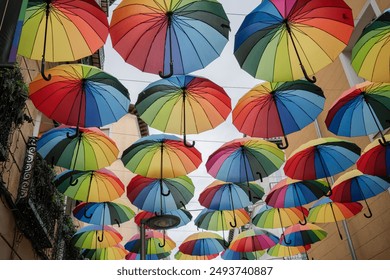 Colorful umbrellas hanging upside down in the street, creating a tunnel effect