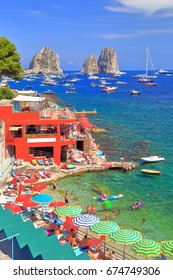 Colorful Umbrellas And People Swimming And Tanning At Marina Piccola In Capri, Capri Island, Italy