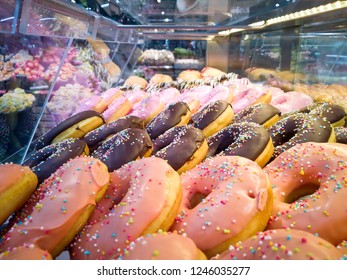 Colorful various flavor donuts with various coating and topping in a glass showcase.