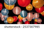 Colorful Various illuminated paper lanterns lights hanging in dark background at Thai Red Cross Fair night market, carnival season