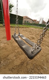 Colorful Vertical Wide Anlge Closeup On An Empty Black Swingset With Chains And Red Pole In A Deserted Children Playgrond