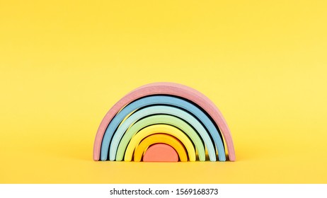 Colorful Waldorf wooden rainbow on yellow background side view, montessori teaching pedagogy
