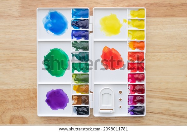 Colorful\
watercolor paints set in watercolor palette on wood. Bright\
multicolored aquarelle paints in paint\
box.
