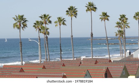 Colorful waterfront cottages in Oceanside, California USA. Multicolor bungalow huts by sea, beachfront lodging. Many vacation houses on beach, ocean waves and palm trees. Summer seascape on sunny day.