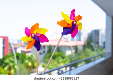 Colorful windmills on balcony in selective focus. Windmills with wings of different colors. Clean energy, LGBTQ colors concept.