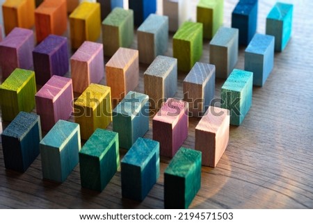 Colorful wooden blocks placed in intervals on a rustic wooden table with incoming light. Diversity, variation, assortment concept. Shallow depth of field.