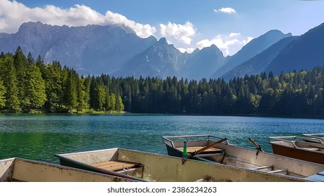 Colorful wooden boats on Fusine Lake (Laghi di Fusine) with scenic view of Mangart and Julian mountain range in Tarvisio, Friuli-Venezia Giulia, Italy, Europe. Water reflection in green alpine lake - Powered by Shutterstock