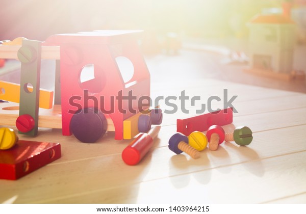 Colorful wooden constructor with details of\
car, screwdriver and screws. Early education. Preschool skills\
concept. Sunlight\
background