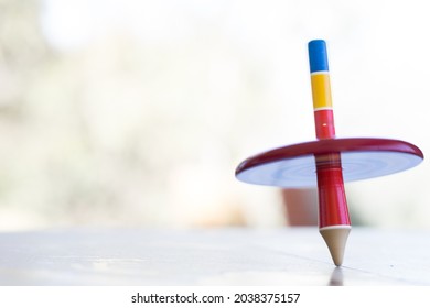 A colorful wooden peg-top or a teetotum with copy space on the left - Powered by Shutterstock