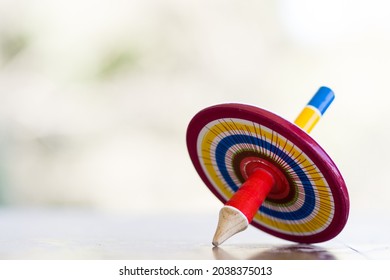 A colorful wooden peg-top or a teetotum on a blurred background - Powered by Shutterstock