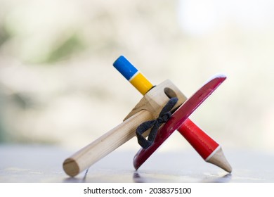 A colorful wooden peg-top or a teetotum on a blurred background - Powered by Shutterstock