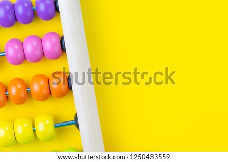 Colorful wooden pink and orange abacus beads on yellow background with copy space for presentation, business financial or accounting profit and loss concept, or use in education school arithmetic.