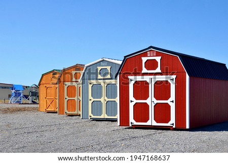 Colorful wooden sheds in row on display. American shed is typically a simple, single-story roofed structure in a back garden or on an allotment that is used for storage, hobbies, or as a workshop. 