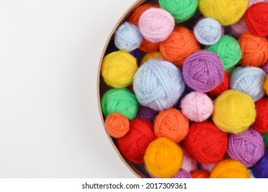 A lot of colorful wool balls of knitted yarn in a round cardboard box on a white background.The concept of handmade work, needlework and the sale of thread.Top view.Flatlаy.Rainbow layout.Copyspace.