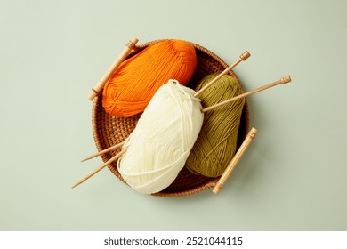 Colorful yarn balls and wooden knitting needles in wicker basket on green background. Knitting concept - Powered by Shutterstock