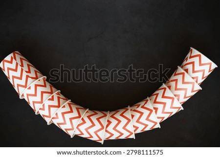 Colorful Zigzag Patterned Cups Arranged in a Curved Shape on Dark Background