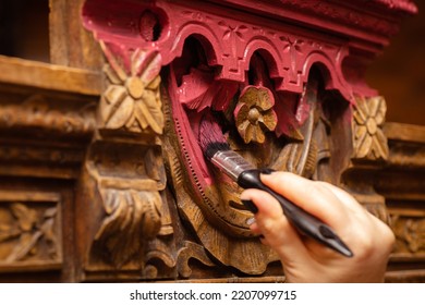 Coloring detailed carved ornaments of old wooden sideboard buffet with brush in pink color with female hand in foreground. New life of old things. Restoration of antique old furniture pieces. - Shutterstock ID 2207099715