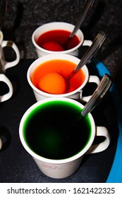 Coloring hard boiled Easter eggs in coffee cups, vertical