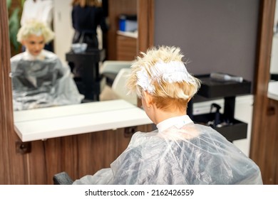 Coloring White Hair With Hair Dye Of The Young Caucasian Blonde Woman Sitting At A Hair Salon, Close Up