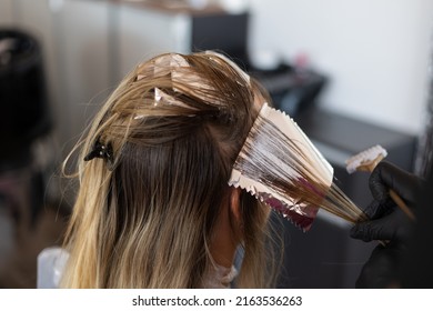 Colorist putting hair dye on a lock of hair with foil. - Shutterstock ID 2163536263