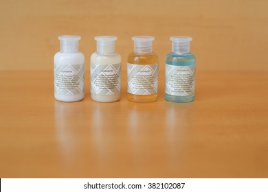 Colorless Bottles Of Bath Gel, Shampoo, Hair Conditioner And Hand Lotion With Ingredients On Wooden Background